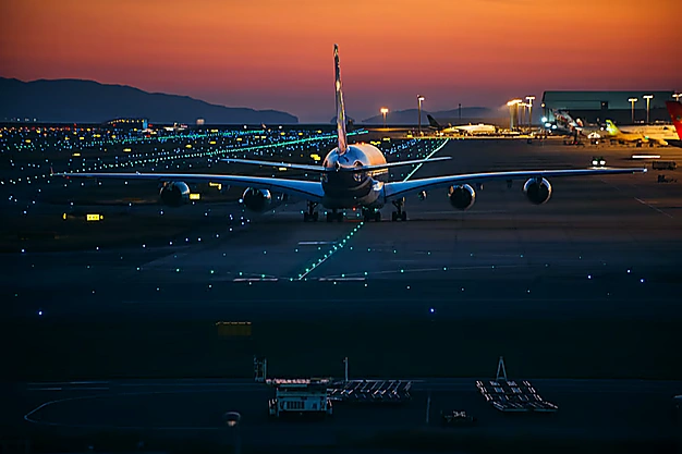 Commercial passenger airplane taxiing on the airport runway at sunset with illuminated runway lights for going for Umrah