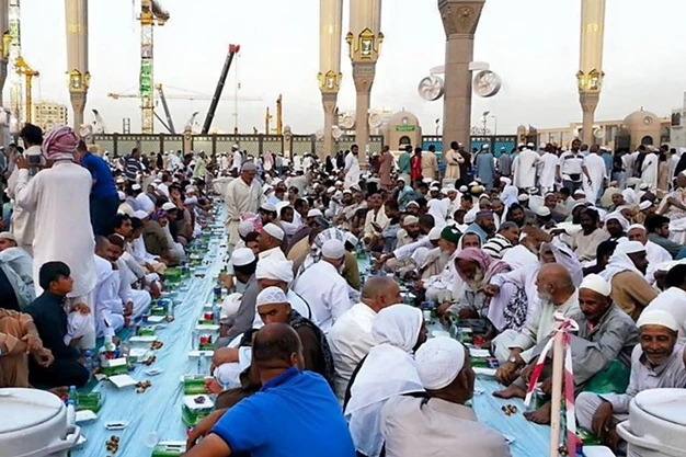 uslim pilgrims sharing Iftar at Al-Masjid e Nabawi in Madinah during Ramadan before breaking their fast as part of their Umrah journey.