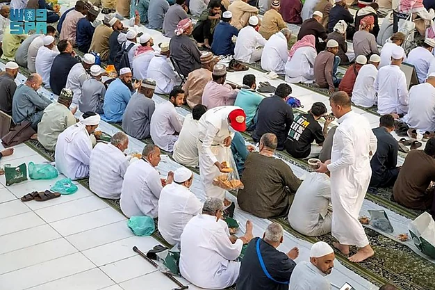 Volunteers serving Iftar meals to Muslim pilgrims at Al-Masjid-an-Nabawi in Madinah during Ramadan as part of their Umrah journey.