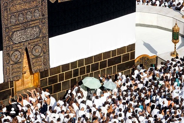 Close-up view of the Holy Kaaba door at Masjid-al-Haram in Makkah with Umrah pilgrims gathered in worship.