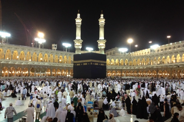 Holy Kaaba at Masjid-al-Haram in Makkah illuminated at night with thousands of pilgrims performing Umrah and Tawaf.