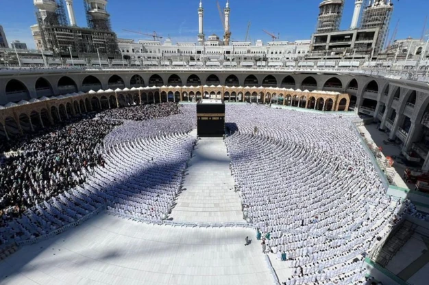 Muslim worshippers offering congregational prayer in front of the Holy Kaaba at Masjid Haram in Makkah during Umrah pilgrimage.