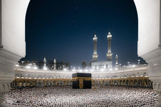 Framed night view of the Kaaba with pilgrims offering Salah at Masjid al Haram in Makkah.