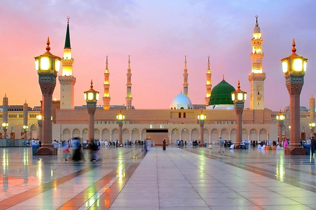 Evening view of Masjid-e-Nabawi with the Green Dome, illuminated minarets and courtyard in Madinah.