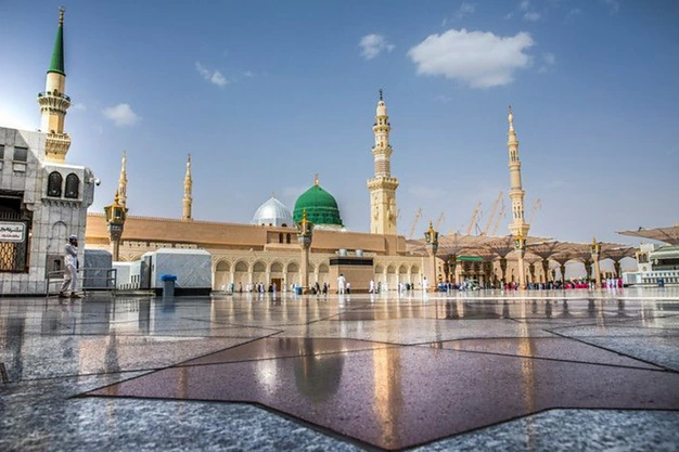 Low-angle view of the Green Dome, white domes, and minarets of Masjid-e-Nabawi in Madinah.