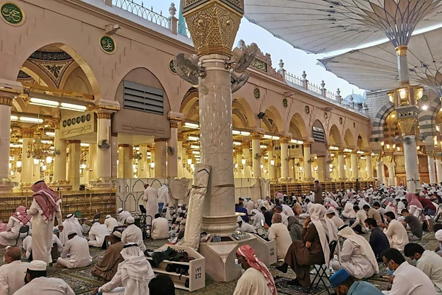 Prayer area in the courtyard of Masjid-e-Nabawi with open umbrellas providing shade for worshippers in Madinah.