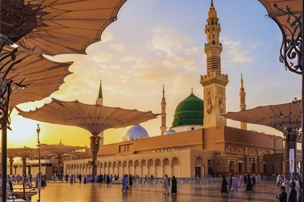 Sunset side view of the open umbrellas at Masjid-e-Nabawi with the Green Dome in Madinah.
