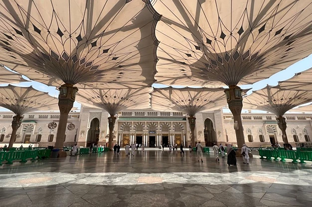Courtyard of Al-Masjid-e-Nabawi in Madinah featuring the iconic giant umbrellas that provide shade for pilgrims and visitors.