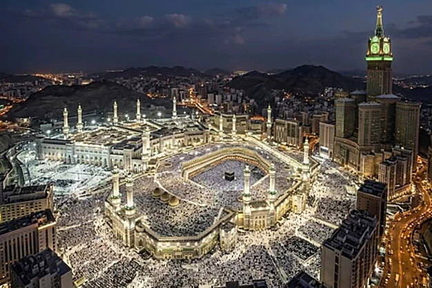 Night view of Masjid al-Haram surrounded by hotels and the illuminated cityscape of Makkah.