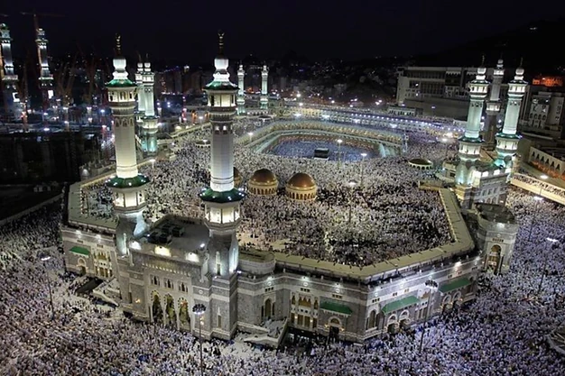 Aerial night view of Masjid al-Haram with the Kaaba and pilgrims performing Tawaf in Makkah.