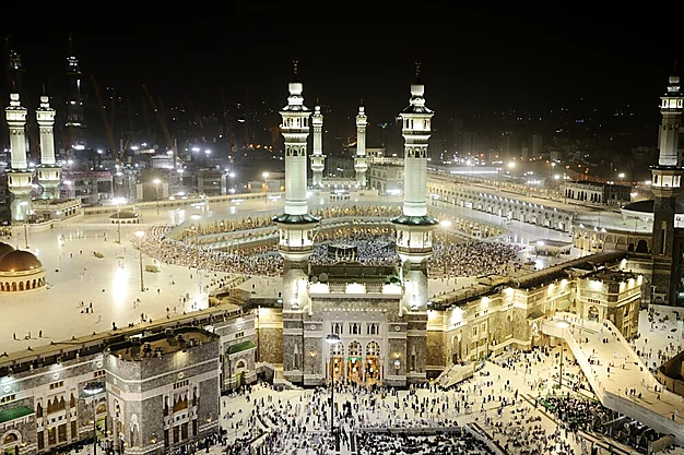 Panoramic night view of Masjid-al-Haram in Makkah with the Kaaba surrounded by Muslim pilgrims performing Umrah at the Grand Mosque.