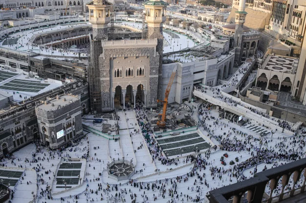 Elevated view of Masjid Haram in Makkah showing the King Fahd Gate entrance, surrounding courtyards and pilgrims walking toward the Holy Kaaba during Umrah.