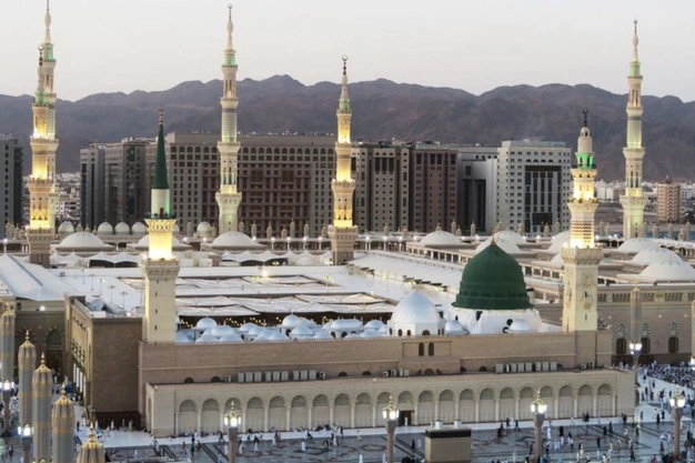 Panoramic view of Masjid-e-Nabawi featuring the iconic Green Dome, minarets and surrounding mountains.