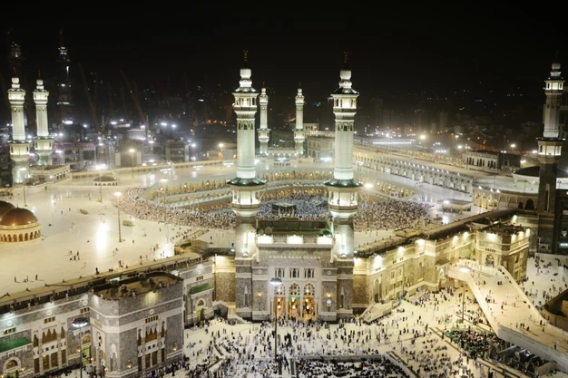 High angle night view of Masjid al Haram with the Kaaba and pilgrims performing Tawaf in Makkah.