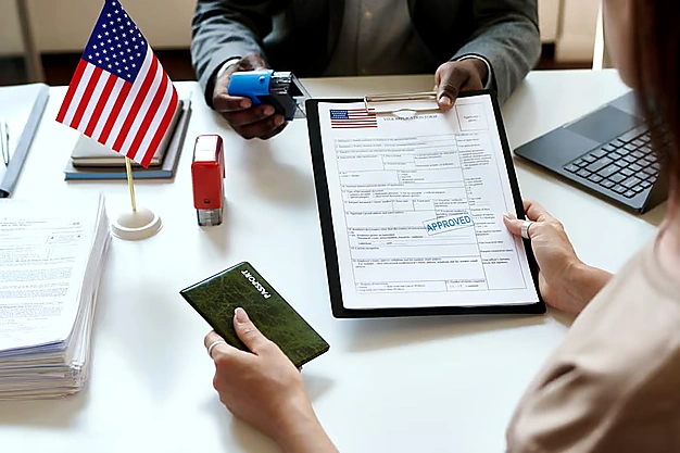 Person holding a passport while receiving an approved visa application document from a visa officer